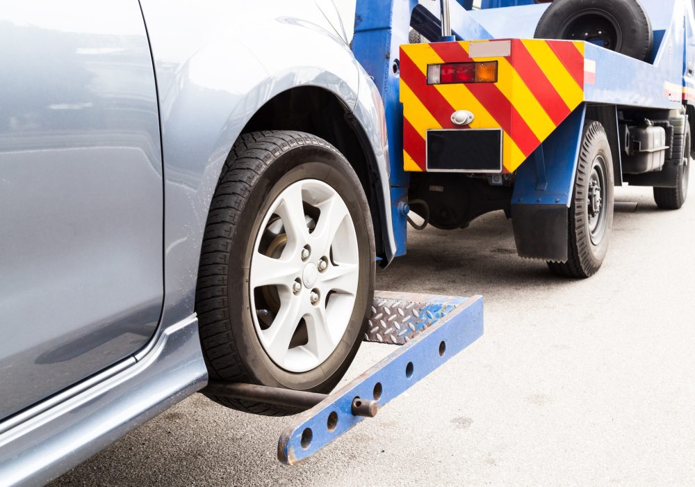 Tow truck towing a broken down car on the street